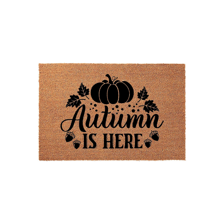 Autumn Is Here coir doormat featuring a rustic pumpkin and acorn design printed in black ink on a natural tan fiber background, creating a festive seasonal entryway decor piece for your front porch during the fall harvest season.