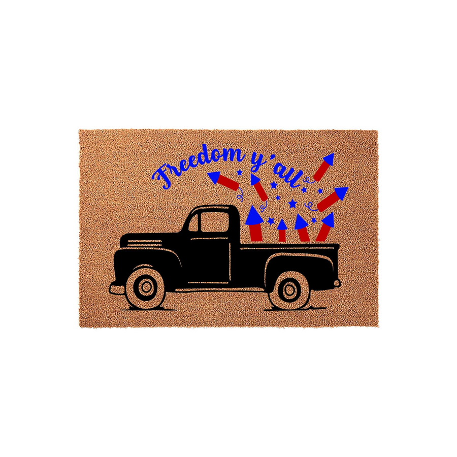 Freedom Y'all Patriotic Truck Doormat featuring a black vintage pickup truck silhouette carrying red and blue fireworks on a natural coir background, perfect for a festive Fourth of July or summer entryway decor display.