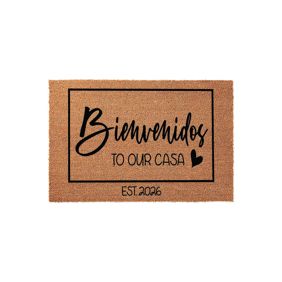 Personalized Bienvenidos to Our Casa coir doormat featuring a black rectangular border, elegant script lettering, and a small heart icon, with the established year 2026 printed at the bottom on a natural brown textured fiber
