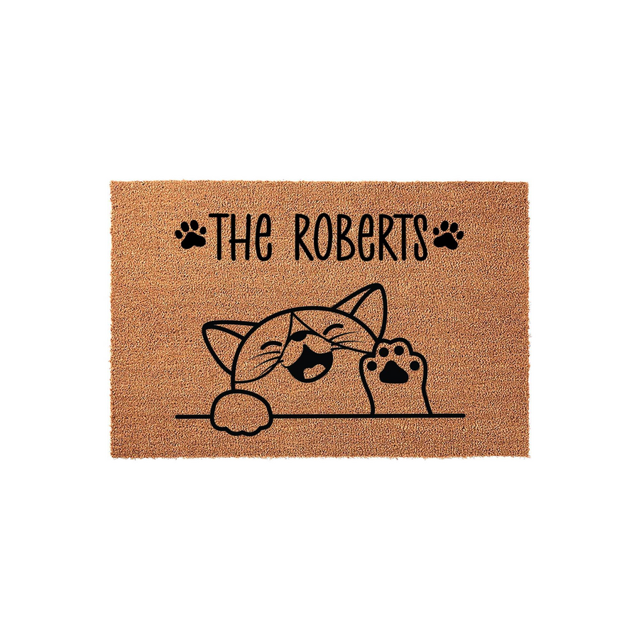 Personalized cat family doormat featuring a cute illustrated kitten waving from behind a line, with space for a custom family name and decorative paw prints on a natural coir fiber background for a welcoming front porch entrance.