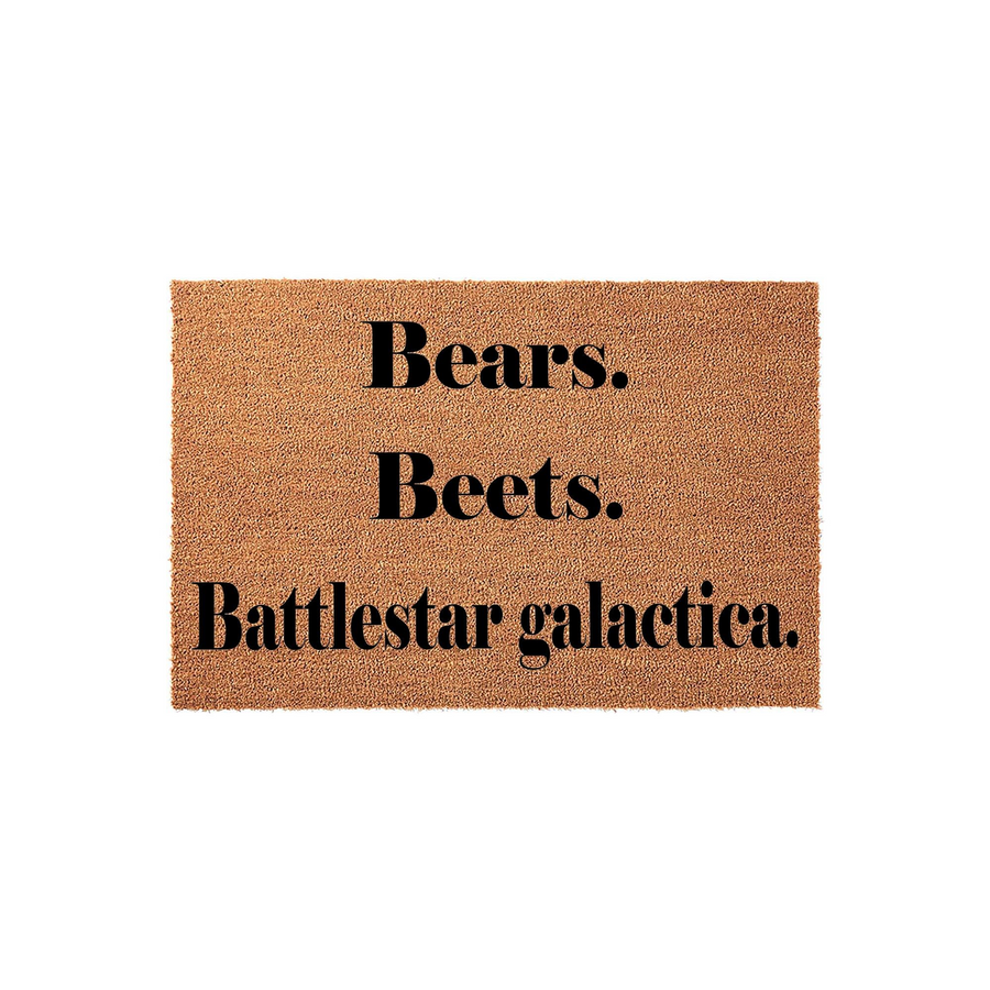 Funny TV show quote doormat featuring the text Bears, Beets, Battlestar Galactica printed in bold black lettering on a natural tan coir fiber mat, perfect for a front porch entrance or a fan of classic office comedy television