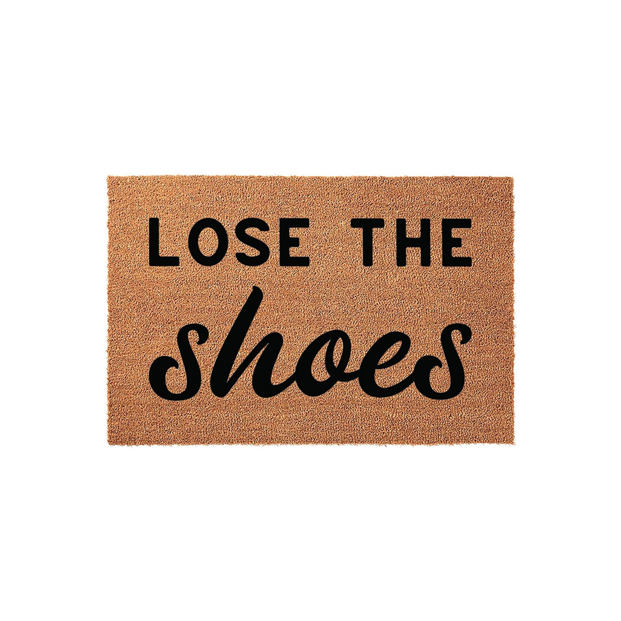 Lose the Shoes coir doormat featuring a natural tan fiber texture and bold black lettering that reads Lose the Shoes, providing a functional and stylish entryway accent for a clean home on a plain white studio background.