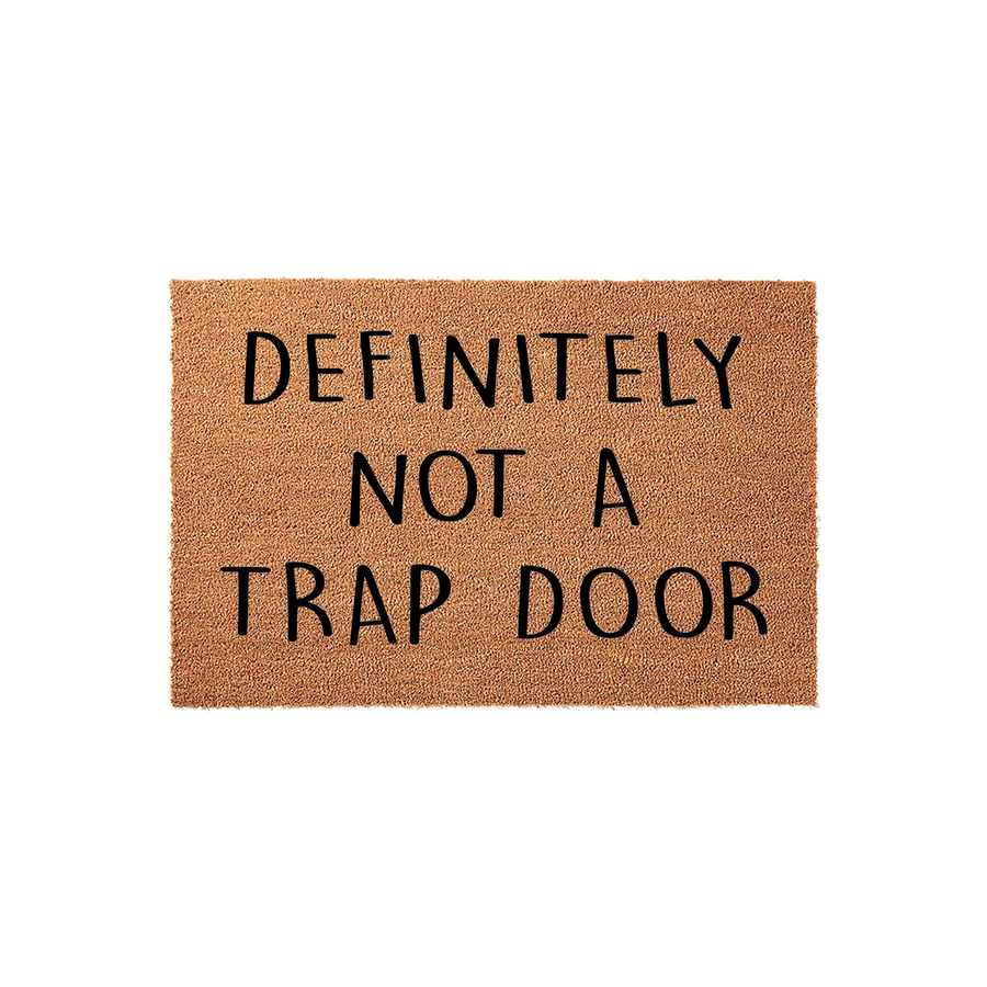 Funny Doormat with the text Definitely Not A Trap Door printed in bold black letters on a natural tan coir fiber background, creating a humorous and welcoming entrance piece for any home front porch or entryway decor.