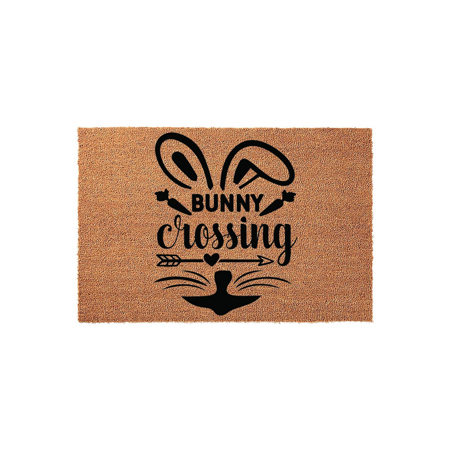 Bunny Crossing Easter Doormat featuring a natural coir texture with a black printed design of rabbit ears, whiskers, and an arrow, creating a festive spring entryway decor piece for your front porch or home entrance during the