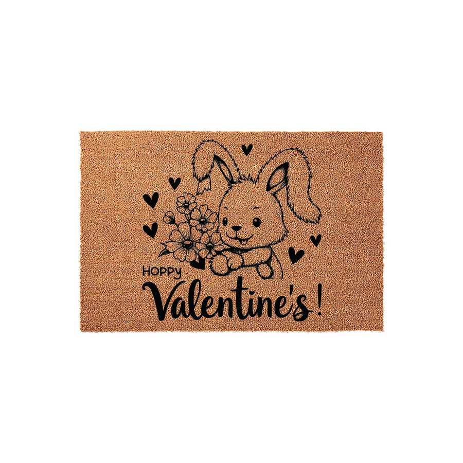 Hoppy Valentine's Day coir doormat featuring a cute illustrated bunny holding a bouquet of flowers, surrounded by small black hearts on a natural tan fiber background, creating a festive seasonal entryway decor piece for your