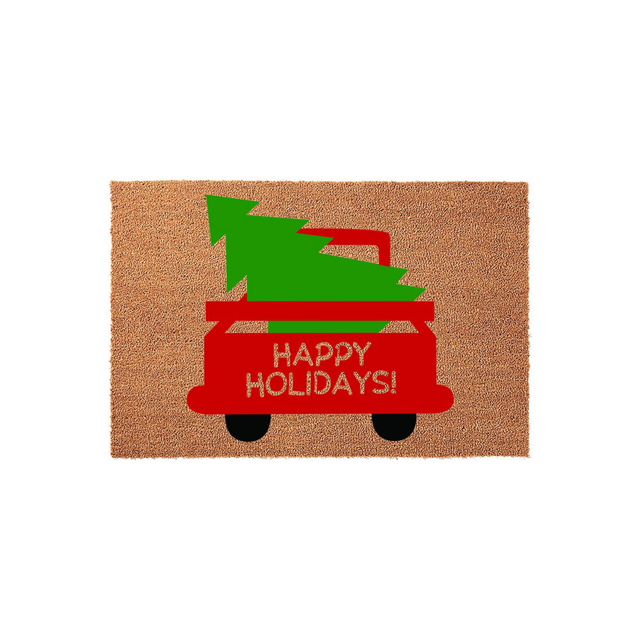 Happy Holidays Christmas doormat featuring a red truck carrying a green pine tree on a natural coir background, providing a festive seasonal welcome for your front porch entryway during the winter holiday season.