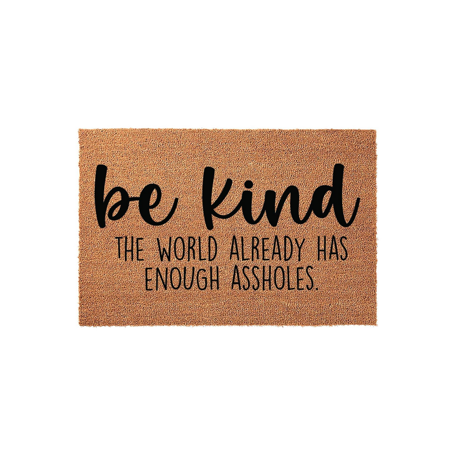 Funny Be Kind Doormat made of natural coir fiber, featuring bold black typography that reads be kind the world already has enough assholes, displayed against a clean white background for a modern home entryway decor aesthetic.