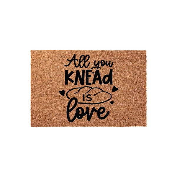 All You Knead Is Love coir doormat featuring a natural brown fiber texture and black printed text with a bread loaf illustration, creating a fun and welcoming entryway decor piece for any home kitchen or front porch area.