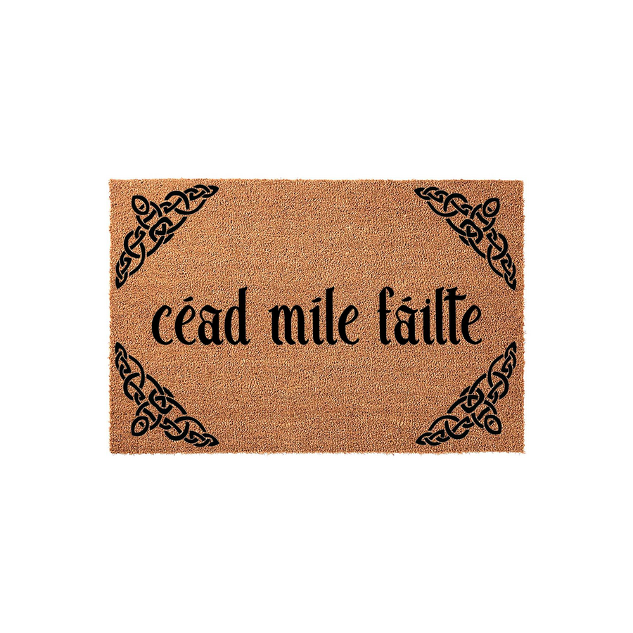 Cead Mile Failte Irish doormat featuring a natural coir fiber texture with black Celtic knotwork designs in each corner, providing a welcoming entrance piece for your home with traditional Gaelic script printed in the center of