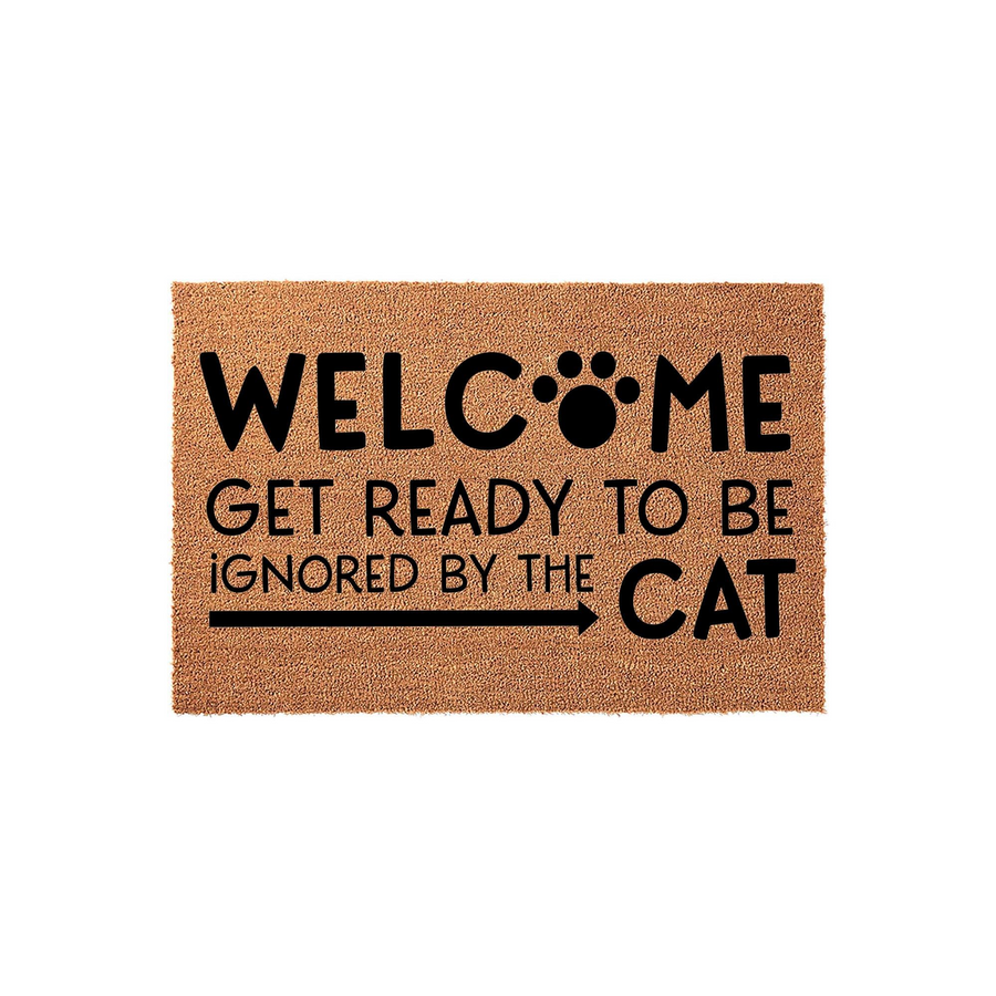 Funny Cat Welcome Doormat featuring a natural coir texture with bold black text that reads Welcome Get Ready To Be Ignored By The Cat, complete with a paw print design and an arrow pointing toward the word cat on a plain white