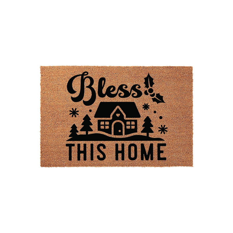 Bless This Home Christmas doormat featuring a natural coir texture with a black printed design of a cozy house, pine trees, snowflakes, and holly leaves, creating a festive winter entryway decor piece for the holiday season.