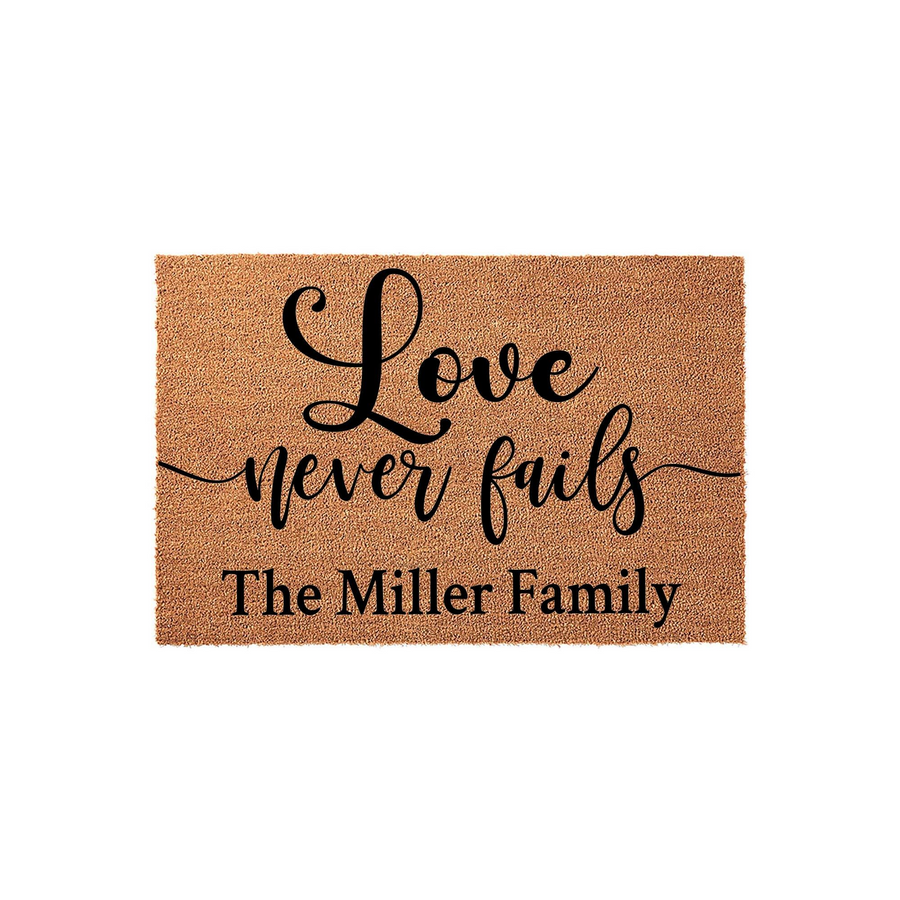 Personalized Love Never Fails Coir Doormat featuring elegant black script lettering on a natural tan fiber background, customized with a family name to create a welcoming entrance for any home or housewarming celebration.