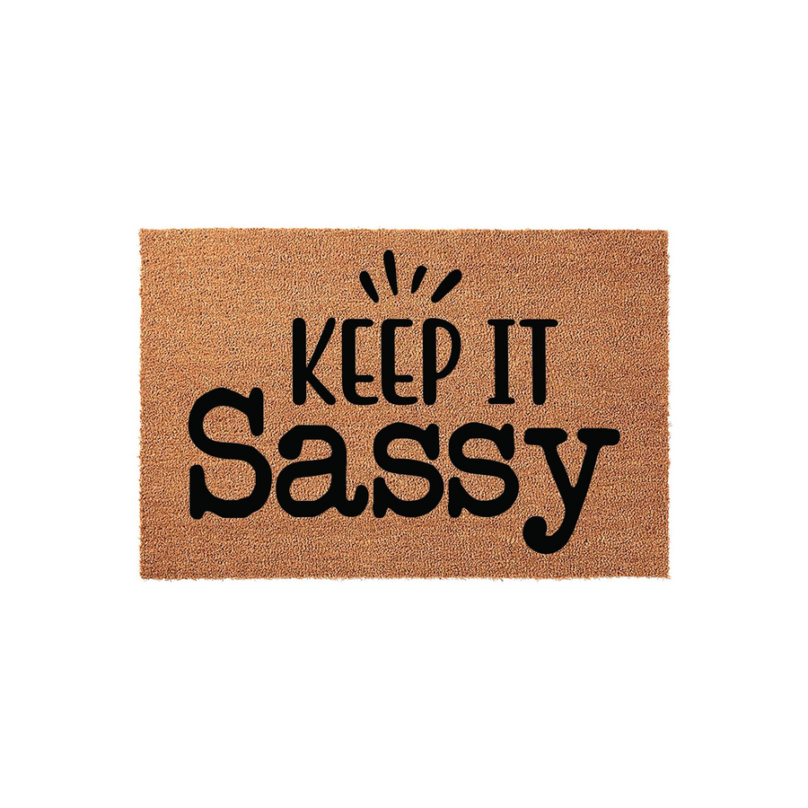 Keep It Sassy coir doormat featuring a natural brown fiber texture and bold black lettering that reads Keep It Sassy with decorative accent marks above the text, displayed against a clean white background for a modern entryway