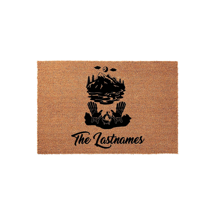 Personalized mountain lake doormat featuring a black graphic of two Adirondack chairs by a campfire with a mountain landscape, customized with a family name in elegant script on a natural tan coir fiber background for a rustic