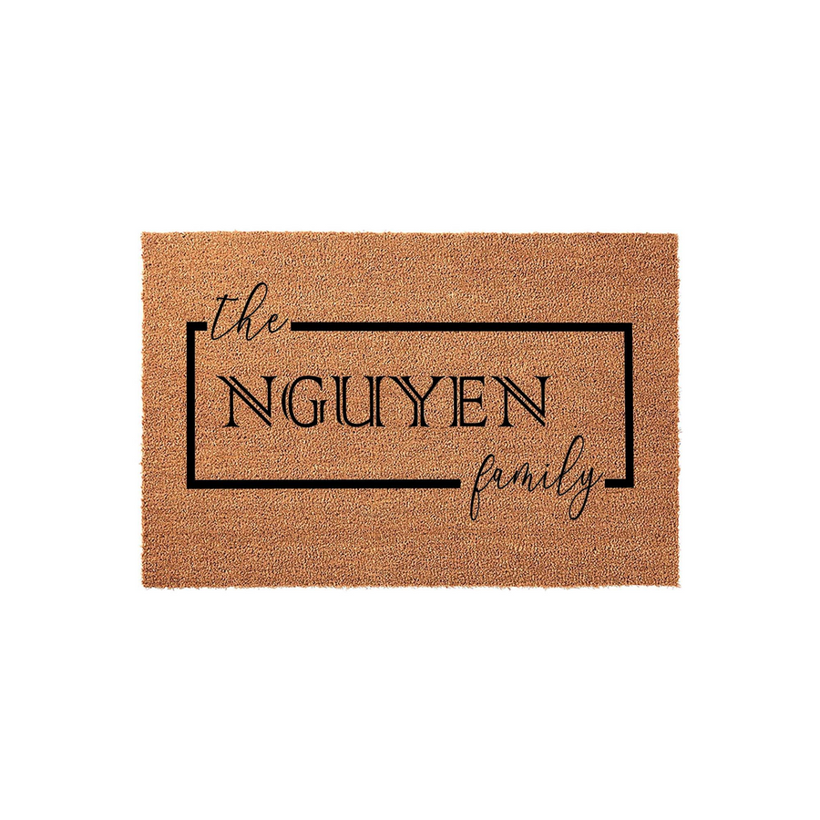 Personalized coir doormat featuring a custom family name inside a clean black rectangular frame, designed with elegant script and modern serif typography to create a welcoming entrance for any home or housewarming celebration.