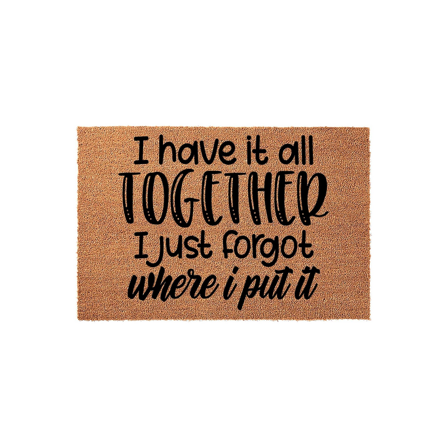 Funny coir doormat featuring the humorous quote I have it all together I just forgot where I put it printed in bold black lettering against a natural tan textured background, making it a witty addition to any home entryway or