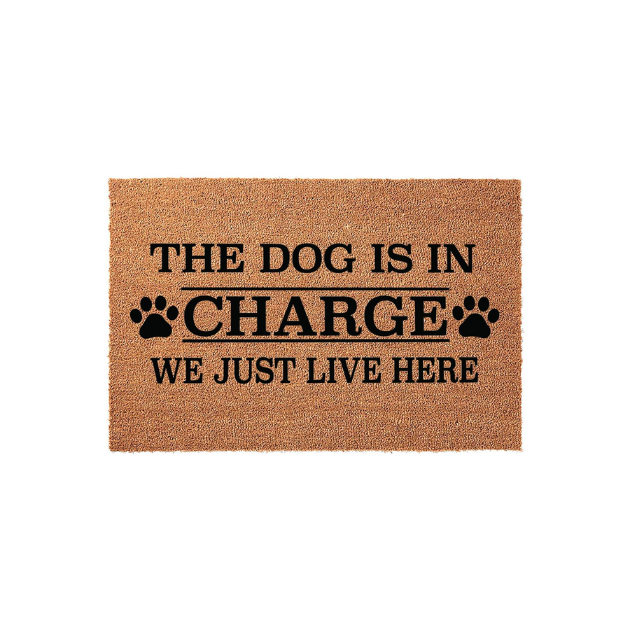 The Dog Is In Charge We Just Live Here coir doormat features bold black text and paw print accents on a natural tan fiber background, making it a humorous and durable welcome mat for any dog lover's front porch or entryway home