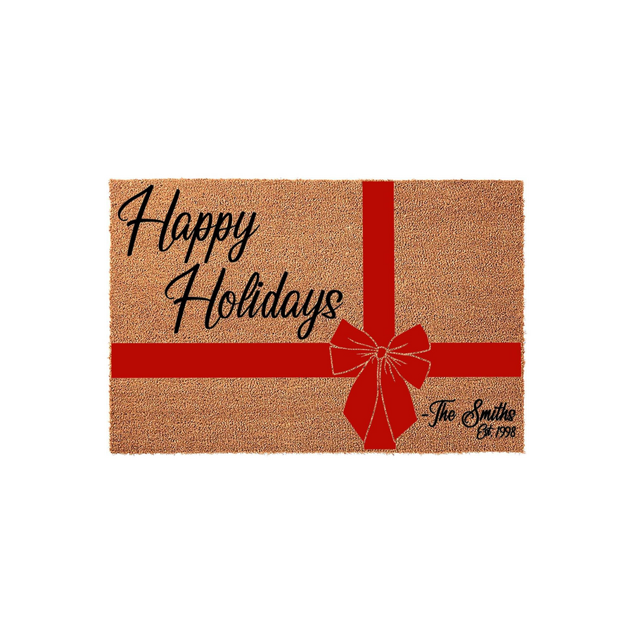Personalized Happy Holidays coir doormat featuring a festive red ribbon and bow design, customized with a family name and established year to create a welcoming entrance for your home during the winter season on a plain white