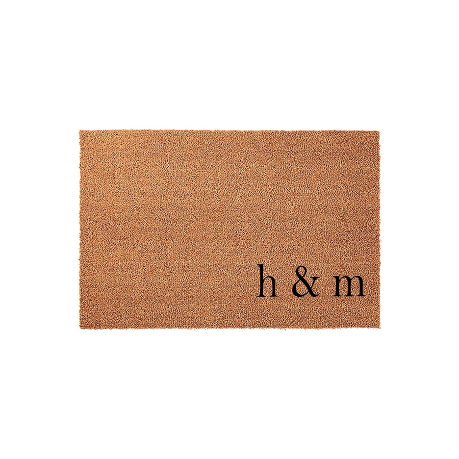 Personalized coir doormat featuring the letters h & m in a classic serif font, set against a clean white background to highlight the natural brown texture of the durable outdoor welcome mat for your front porch entry.