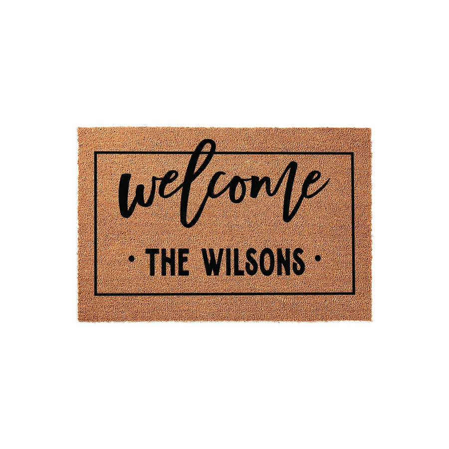 Personalized family name coir doormat featuring a classic rectangular border, elegant script lettering for the word welcome, and clean sans-serif text for the custom family name on a natural brown textured fiber background.