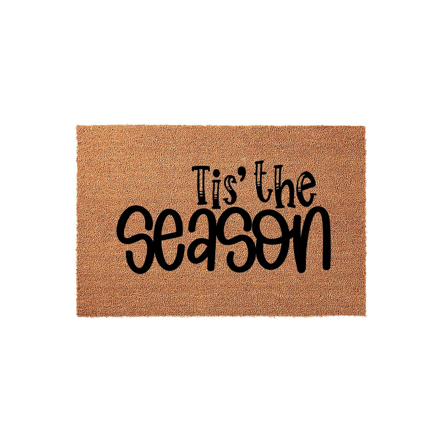 Tis the Season Christmas doormat made of natural coir fiber with a rectangular shape, featuring bold black lettering centered on the textured brown surface to welcome guests to your home during the festive holiday winter season.