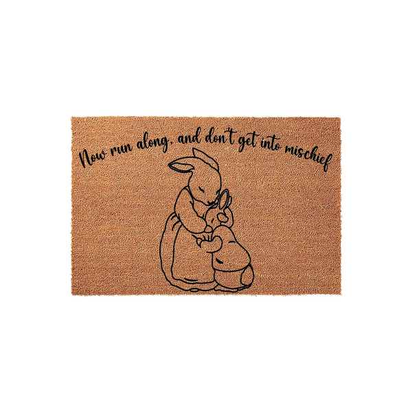 Peter Rabbit themed coir doormat featuring a black line art illustration of a mother bunny hugging her child, with the text Now run along and don't get into mischief printed in a whimsical script font on a natural tan fiber