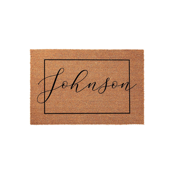 Personalized family name coir doormat featuring a clean black rectangular border and elegant script lettering in the center, set against a plain white background to highlight the natural texture of the durable outdoor welcome mat.