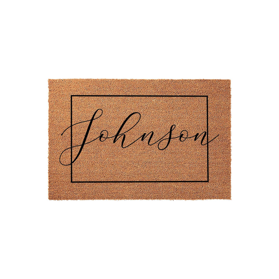 Personalized family name coir doormat featuring a clean black rectangular border and elegant script lettering in the center, set against a plain white background to highlight the natural texture of the durable outdoor welcome mat.