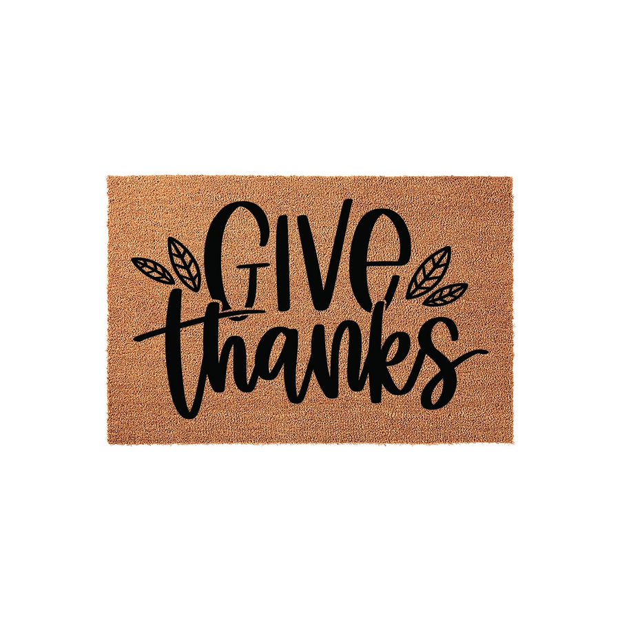 Give Thanks coir doormat featuring a natural tan fiber texture with bold black script lettering and decorative leaf accents, creating a festive fall entryway decor piece for your front porch during the Thanksgiving holiday season.