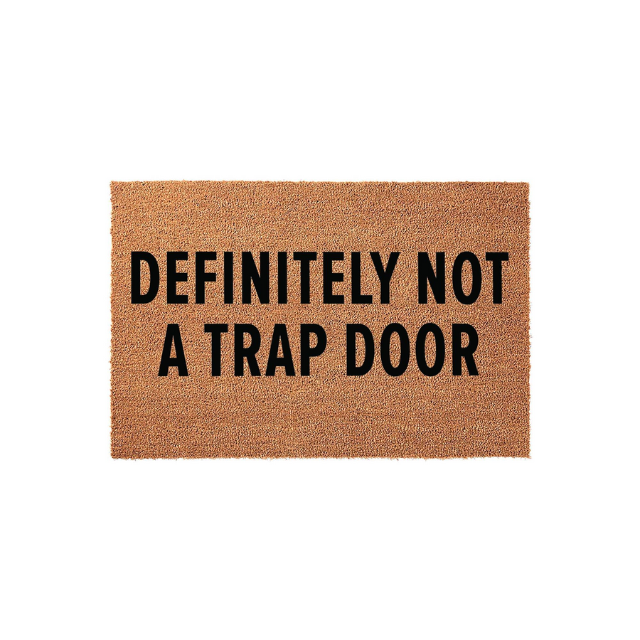 Funny Definitely Not A Trap Door coir doormat featuring bold black text printed on a natural brown coconut fiber mat, providing a humorous and welcoming entrance for your front porch or home entryway on a clean white background.