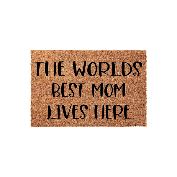 Worlds Best Mom Lives Here coir doormat featuring a natural brown fiber texture and bold black lettering, providing a welcoming and celebratory entrance piece for a home that honors a beloved mother on a clean white studio