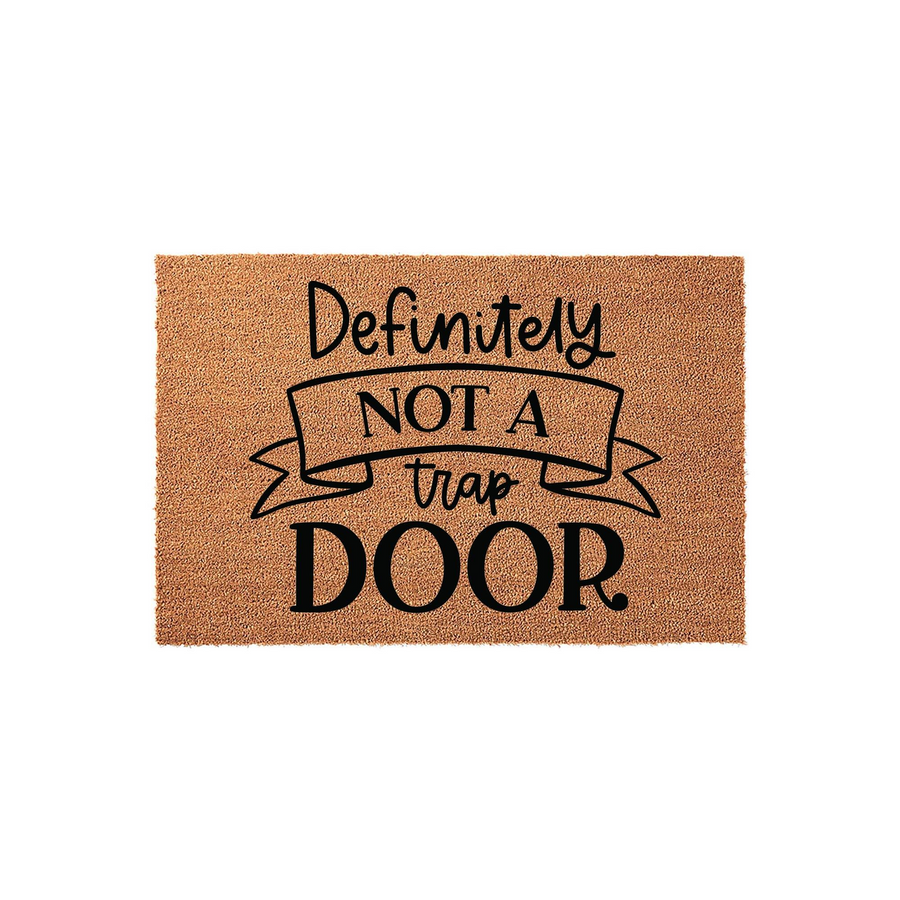 Funny Definitely Not A Trap Door doormat made of natural coir fiber, featuring bold black text and a decorative ribbon graphic centered on a rectangular mat against a clean white background for a humorous home entryway accent.