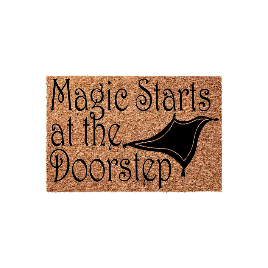 Magic Starts at the Doorstep coir doormat featuring a whimsical black flying carpet graphic printed on a natural brown fiber background, creating a fun and welcoming entrance for any home with a touch of fantasy-inspired decor.