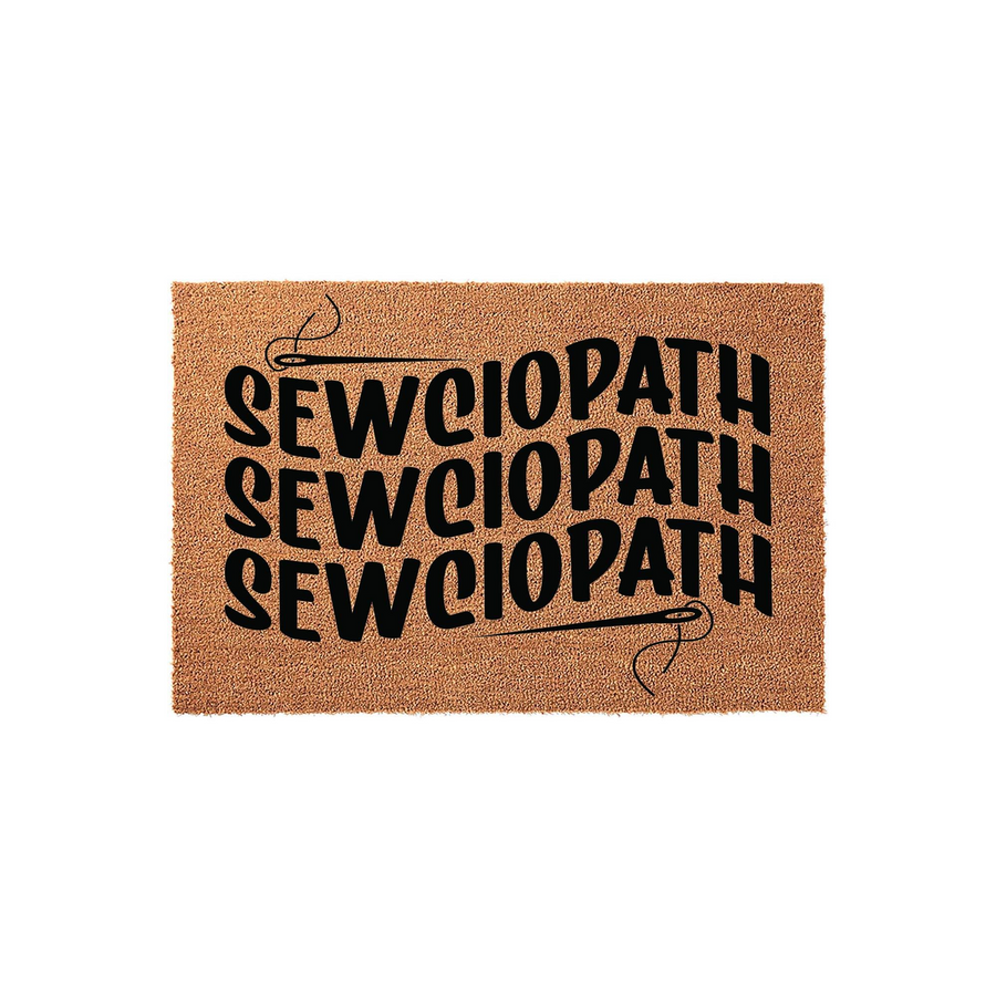 Sewciopath Coir Doormat featuring a humorous sewing-themed design with bold black text and a needle graphic, set against a natural tan fiber background that is ideal for a craft room or a sewing enthusiast's home entryway.