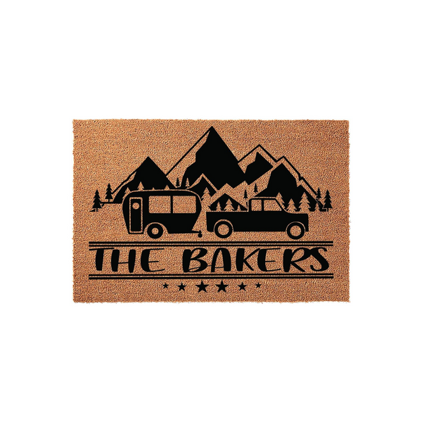 Personalized Camping Doormat featuring a black graphic of a truck towing a camper trailer in front of mountain peaks, with a custom family name printed below the design on a natural tan coir fiber background for a rustic outdoor