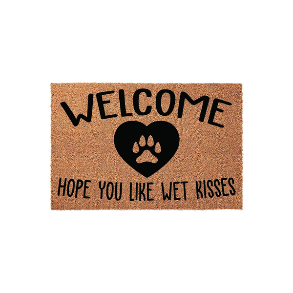 Dog lover welcome doormat made of natural coir fiber, featuring a black heart icon with a paw print in the center and the text Welcome Hope You Like Wet Kisses printed in a bold, playful font against a plain white background.