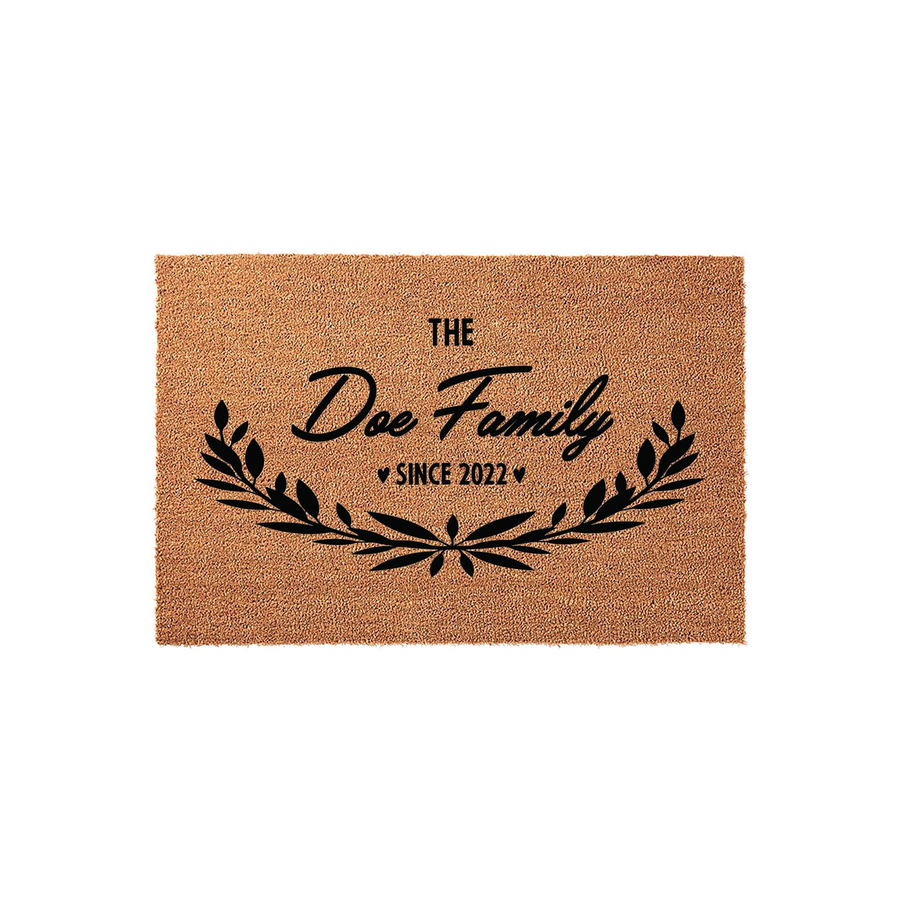 Personalized family name coir doormat featuring a rustic leaf wreath design, black printed text that reads The Doe Family Since 2022, and a durable natural fiber texture for a welcoming front porch entrance decor piece.