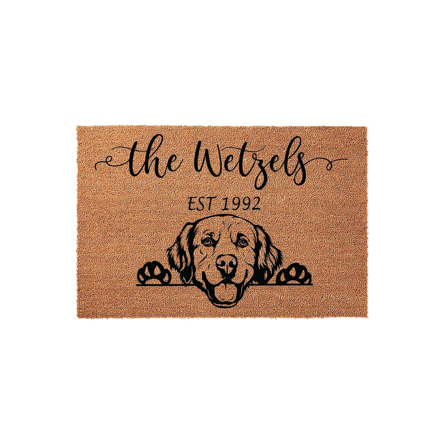Personalized Golden Retriever doormat featuring a cute dog illustration peeking over the edge, customized with a family name and established year printed in black ink on a natural tan coir fiber mat against a clean white