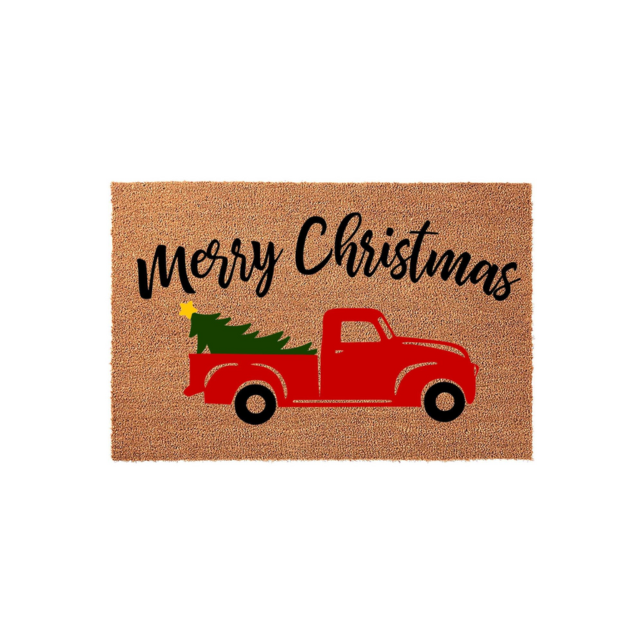 Merry Christmas red truck doormat featuring a festive vintage pickup carrying a green pine tree on a natural coir background, creating a charming holiday entryway decor piece for your front porch during the winter season.
