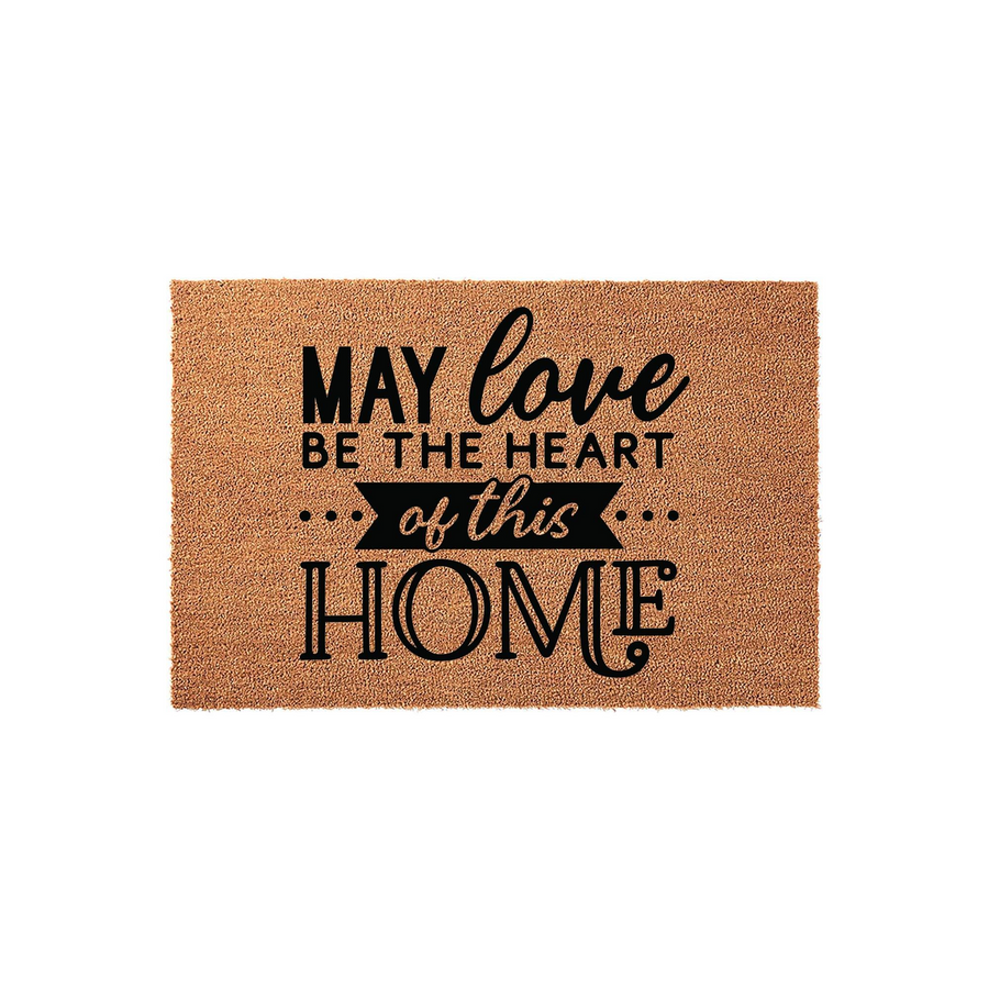May Love Be The Heart Of This Home coir doormat featuring a natural tan fiber texture and bold black typography, creating a welcoming entryway decor piece that adds a warm and inviting touch to any front porch or house entrance.