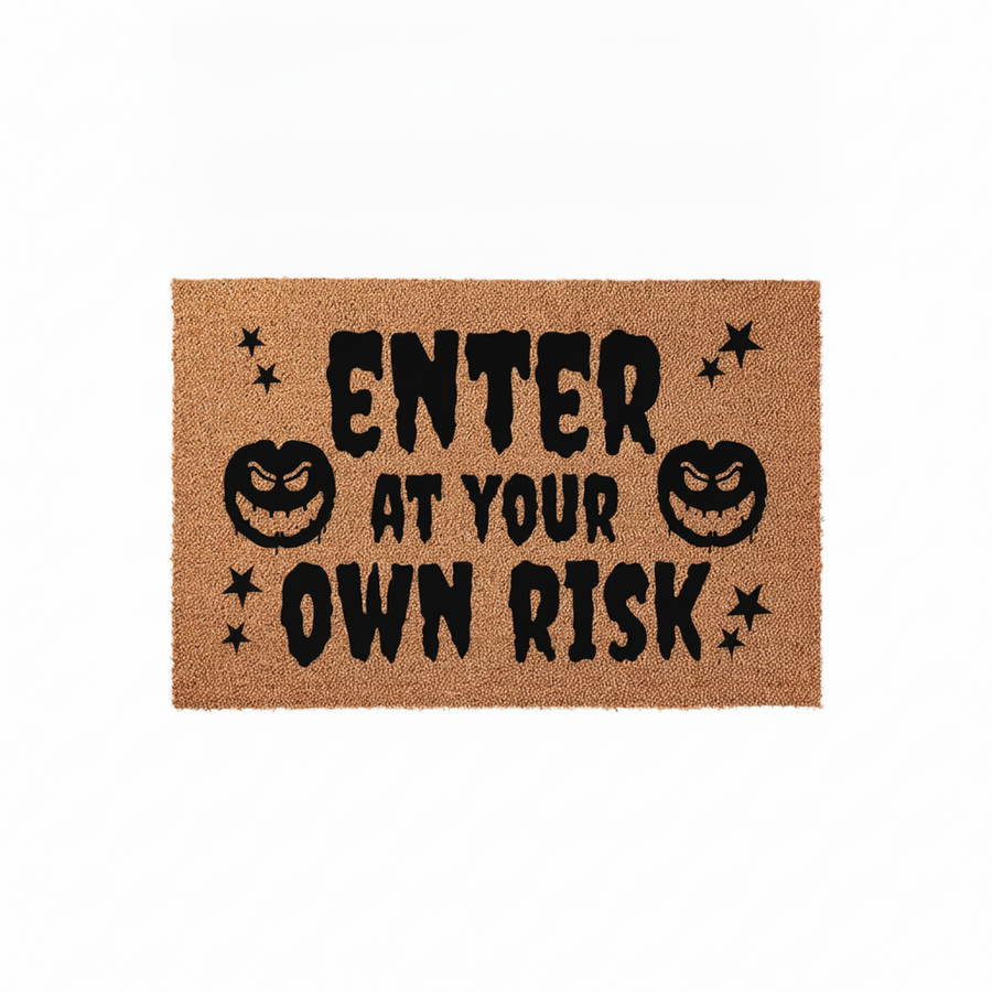 Enter At Your Own Risk Halloween Doormat featuring a natural coir fiber texture with black text and spooky jack-o-lantern pumpkin graphics, creating a fun and festive entryway decor piece for the fall season and October holiday