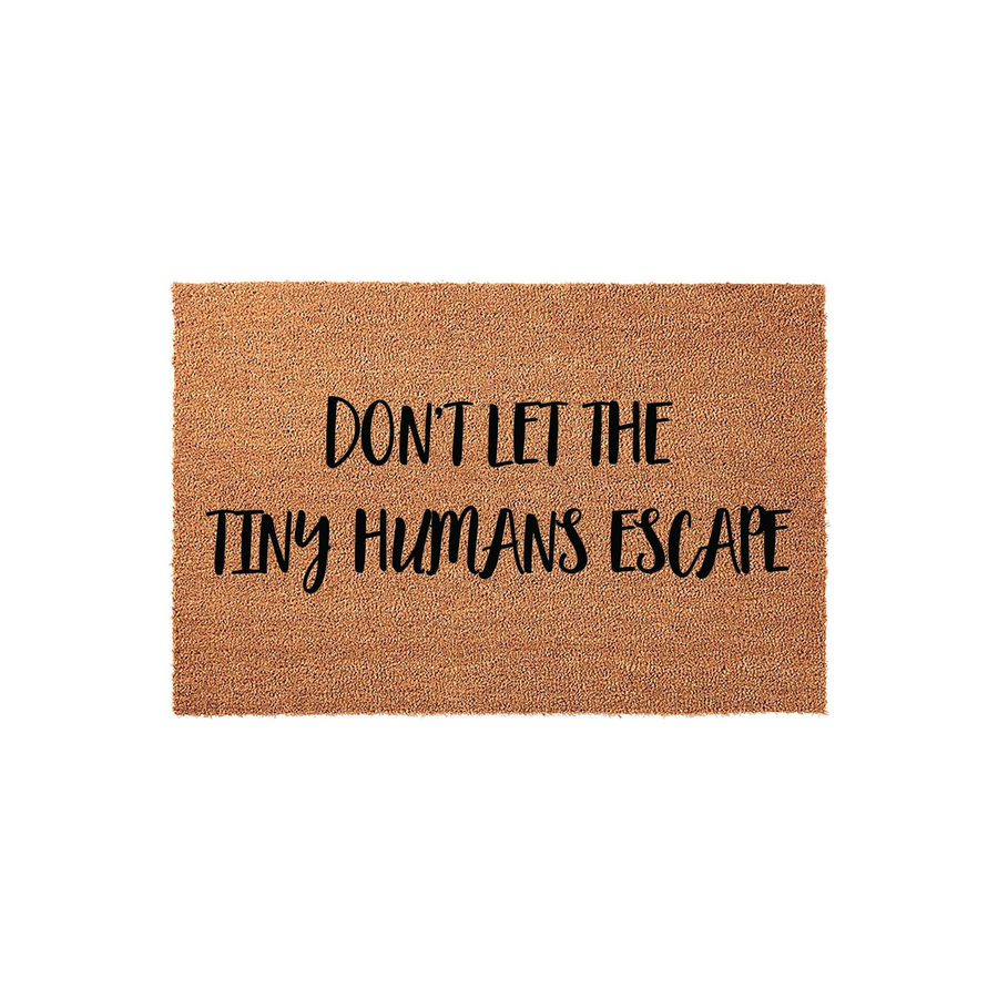Funny Tiny Humans Escape doormat made of natural coir fiber with a textured brown surface, featuring bold black lettering that warns visitors not to let the kids out, displayed against a clean white studio background for a modern