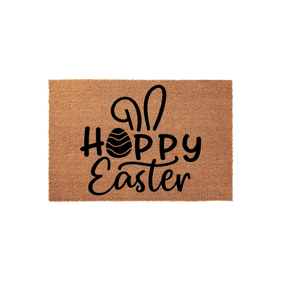 Hoppy Easter coir doormat featuring a natural brown fiber texture with black text that reads Hoppy Easter, accented by a decorative bunny ear design and a striped egg replacing the letter O for a festive spring holiday home
