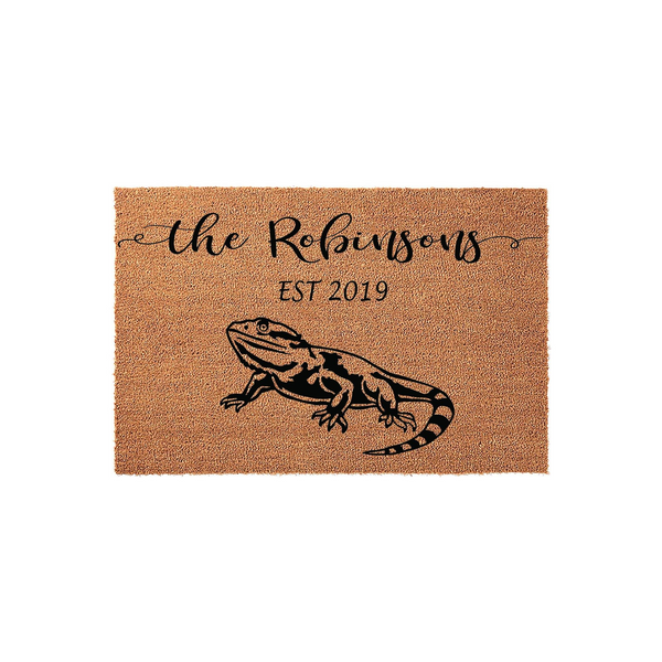 Personalized Bearded Dragon Doormat featuring a black graphic of a lizard on a natural coir mat, customized with a family name and established year in elegant black script and serif fonts against a plain white studio background.