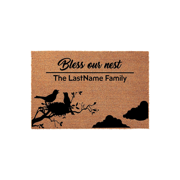 Personalized Bless Our Nest coir doormat featuring a black silhouette of two birds in a nest on a tree branch, with customizable family name text printed above the birds on a natural brown textured fiber background for a home