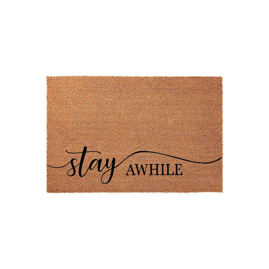 Stay Awhile coir doormat featuring a natural tan fiber texture and elegant black script lettering that reads stay awhile, providing a welcoming front porch decor accent for your home entrance on a clean white studio background.