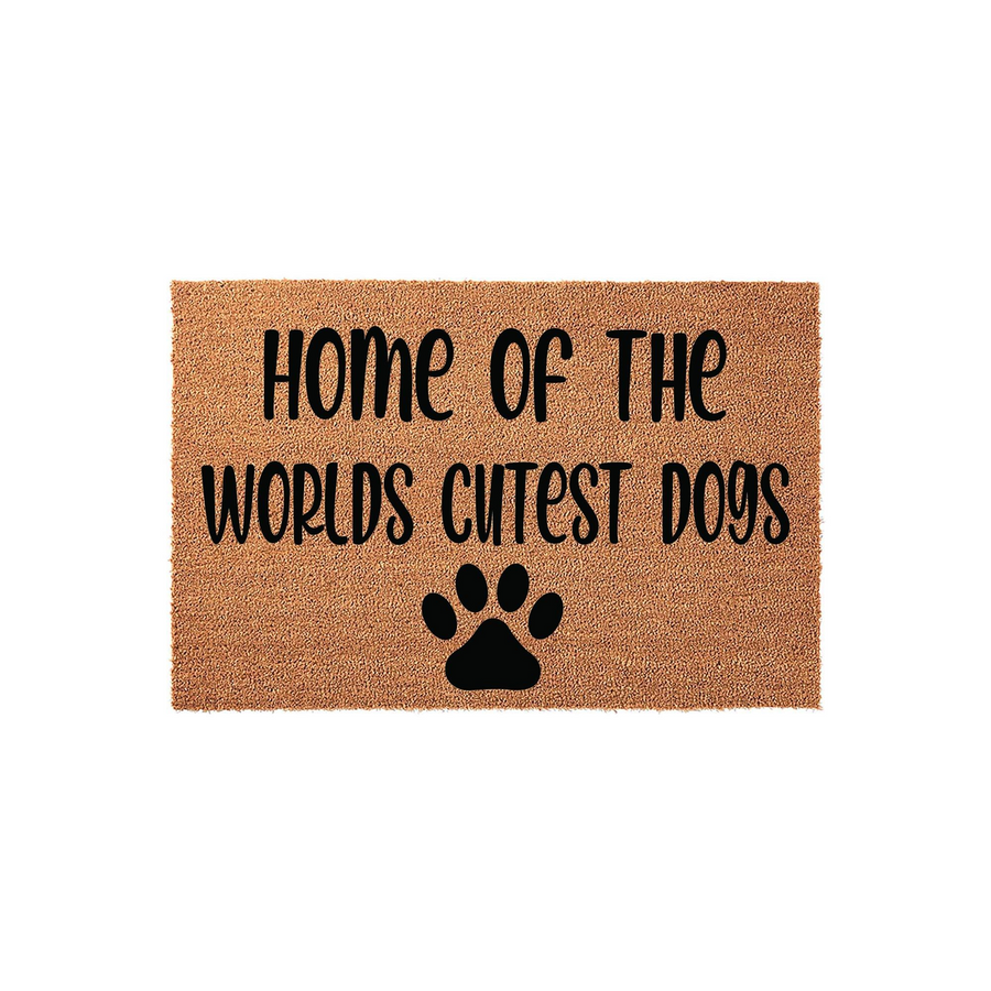 Home of the Worlds Cutest Dogs coir doormat featuring a natural tan fiber texture and bold black lettering that reads Home of the Worlds Cutest Dogs, accented by a single black paw print icon centered at the bottom on a white