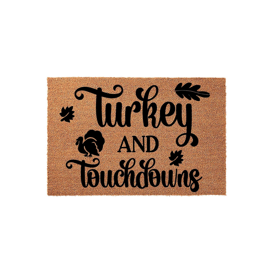 Turkey and Touchdowns Thanksgiving doormat featuring a natural coir texture with black script lettering, a turkey silhouette, and autumn leaf accents for a festive fall entryway decor piece that welcomes guests to your home.