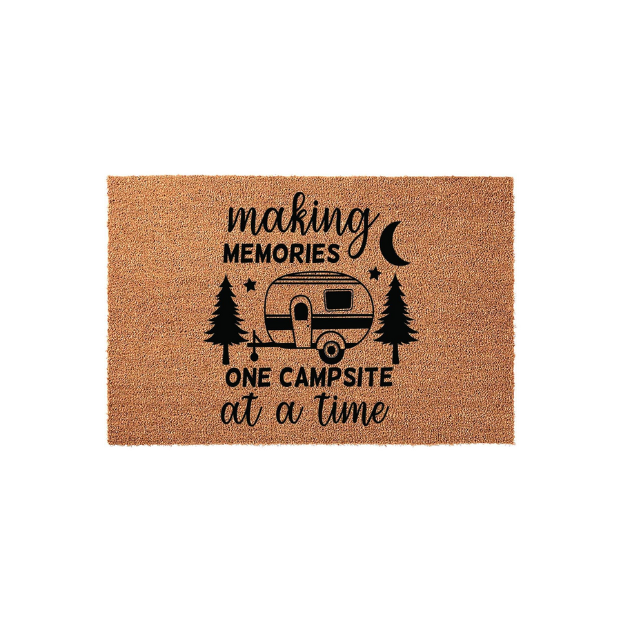 Camping Themed Coir Doormat featuring a vintage camper trailer, pine trees, and a crescent moon graphic with the text making memories one campsite at a time printed in black ink on a natural brown textured fiber background.