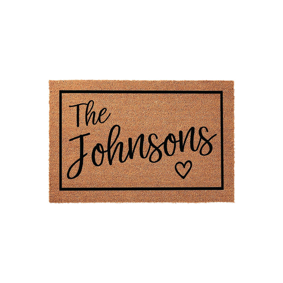 Personalized family name coir doormat featuring a black rectangular border, elegant script lettering for the family name, and a small heart icon, all set against a natural brown textured coir background for a welcoming front
